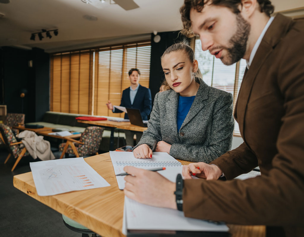 A group of business coworkers work together in a bright, professional space.