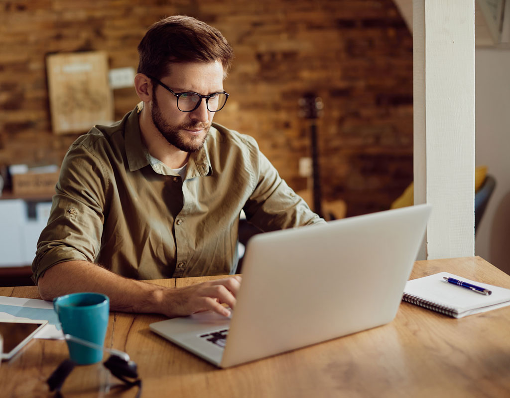 Freelance worker using laptop and typing an e-mail while working at home.