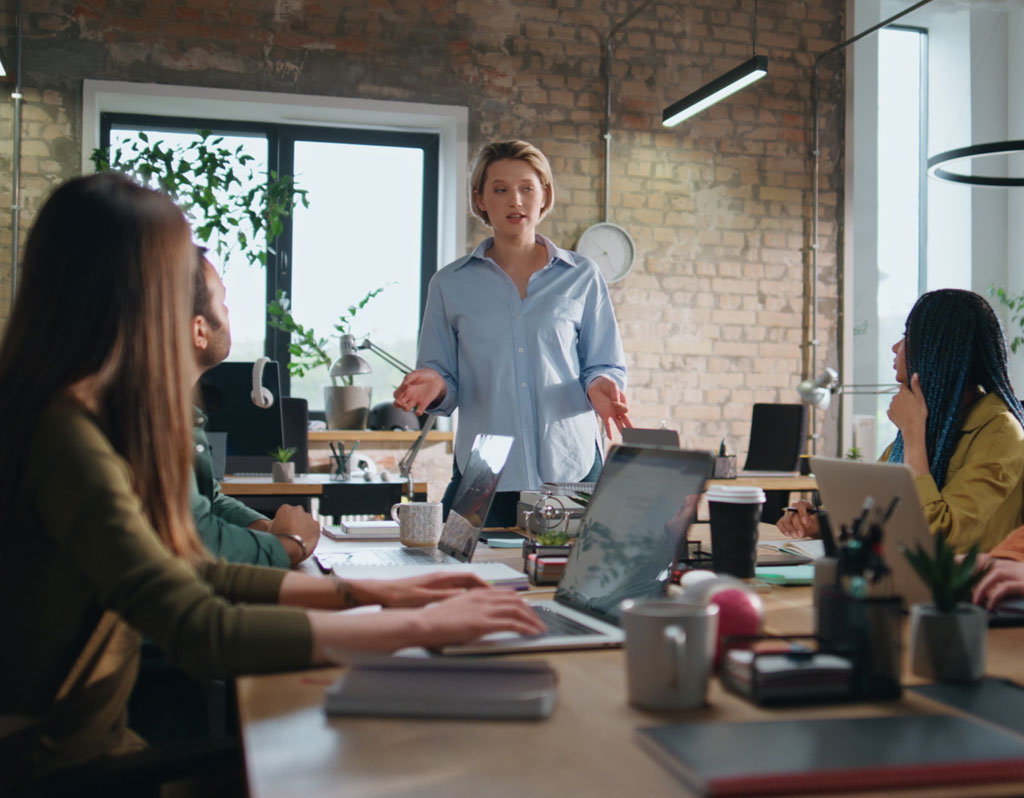 Professional business consultant explaining strategy to diverse office workers in boardroom.